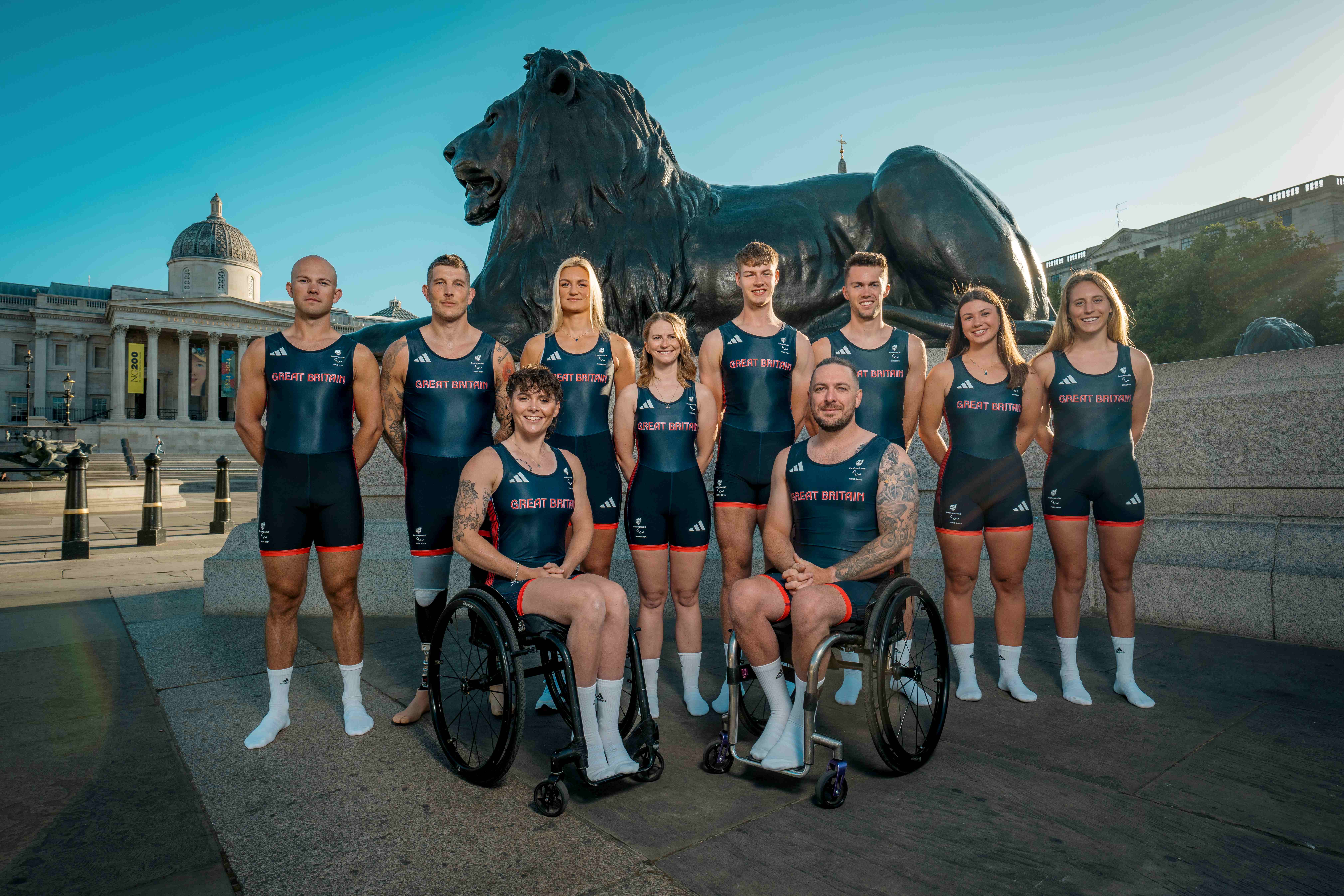 Erin and team members pose in front of a large bronze lion.