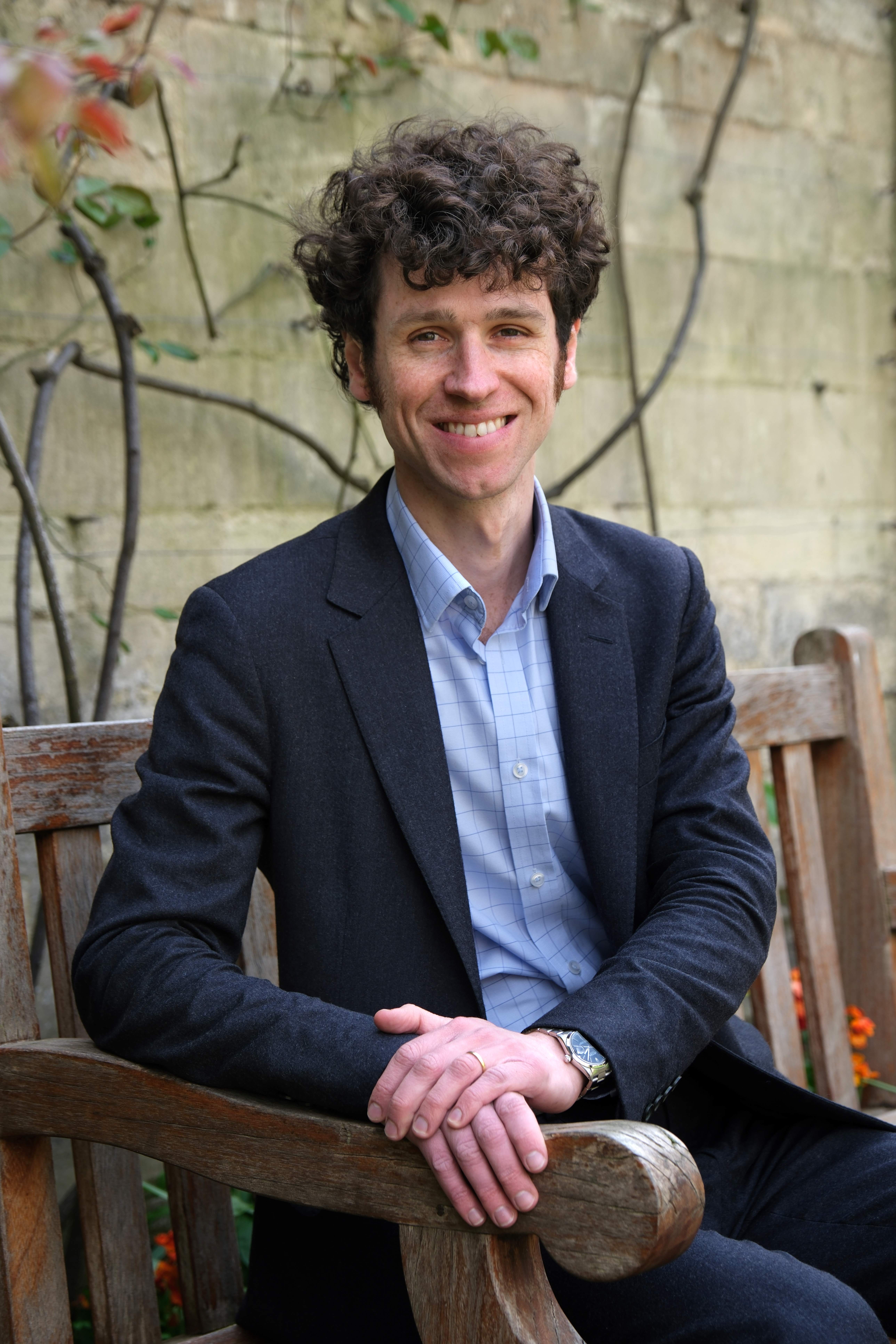 Professor Fitzroy Morrissey sitting on a bench and smiling.